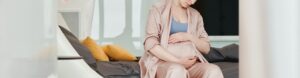 Grávida sentada a segurar a barriga